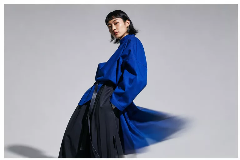 Model in a cobalt coat sweeping past in motion.